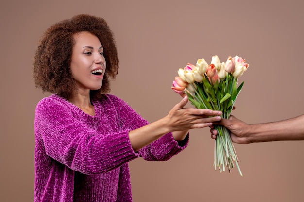 Mulher jovem feliz recebendo flores e parecendo satisfeita