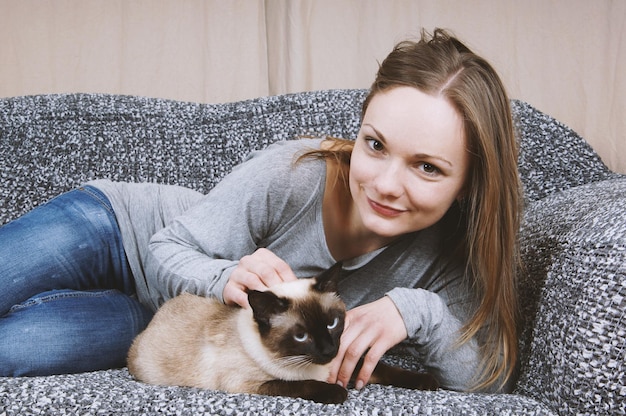 Mulher jovem feliz relaxando no sofá com gato