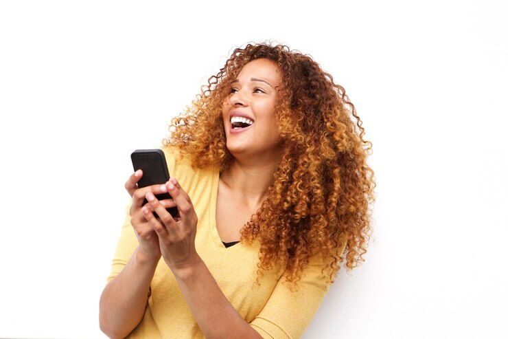 mulher jovem feliz rindo com o celular contra um fundo branco