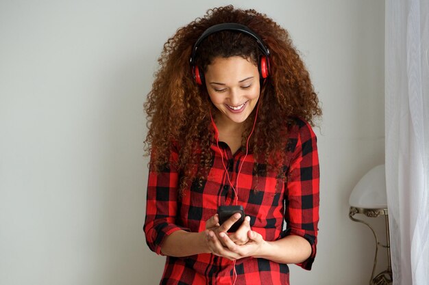 Foto mulher jovem feliz segurando um celular e ouvindo música com fones de ouvido