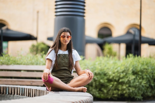 Mulher jovem feliz sentada ao ar livre em posição de ioga