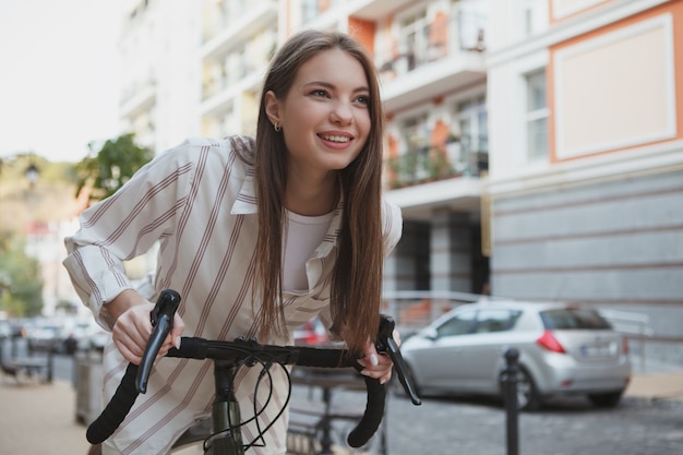 Mulher jovem feliz sorrindo com alegria, andando de bicicleta, copie o espaço