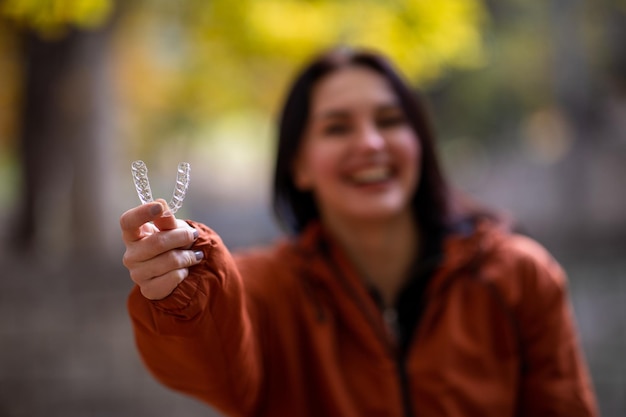 Foto mulher jovem feliz sorrindo com alinhador de dentes invisível durante o outono no parque