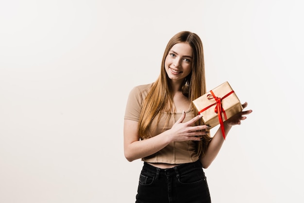 Mulher jovem feliz sorrindo e segurando presente e presente recebido no aniversário ou outro feriado Celebração do evento Menina alegre com caixa de presente com presente no fundo branco