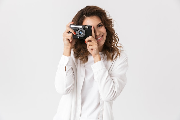 Mulher jovem feliz tirando uma foto com uma câmera fotográfica isolada