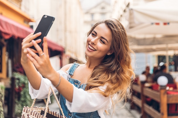 Mulher jovem feliz tomando selfie. Mulher tirando foto de selfie com um smarphone na cidade