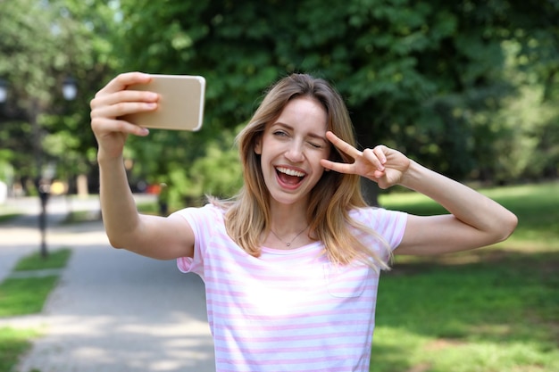 Mulher jovem feliz tomando selfie no parque