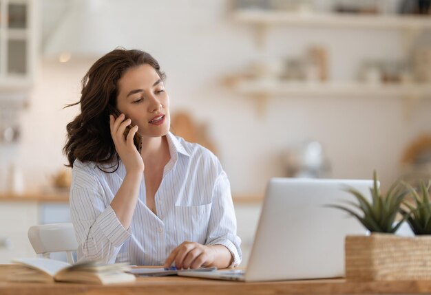 Mulher jovem feliz trabalhando, assistindo ao webinar, podcast no laptop, tendo uma conversa remota.