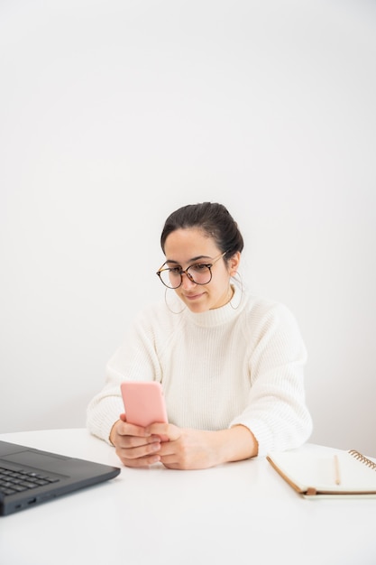 Mulher jovem feliz usando smartphone e trabalhando em casa