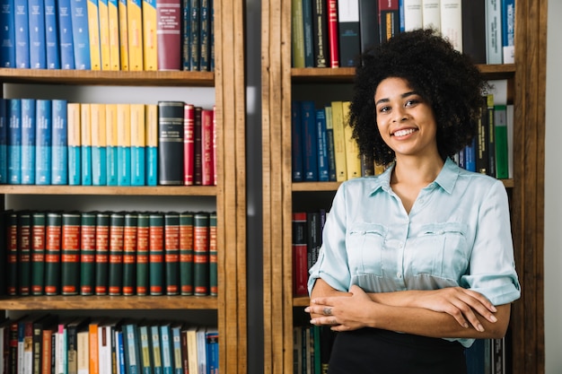 Mulher jovem, ficar, perto, estante de livros, em, escritório