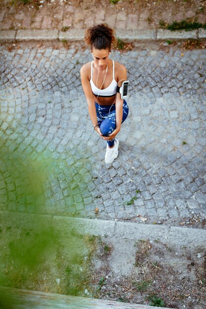 Mulher jovem fitness com fones de ouvido fazendo exercícios de alongamento.