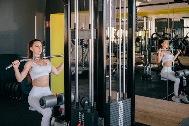 Mulher jovem fitness com máquina de exercício no ginásio