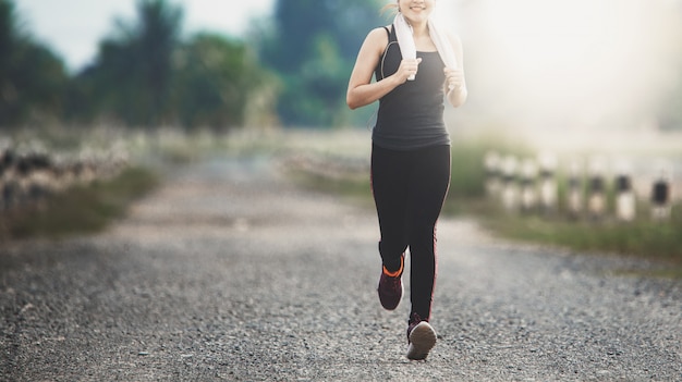 Foto mulher jovem fitness correndo na estrada de manhã.