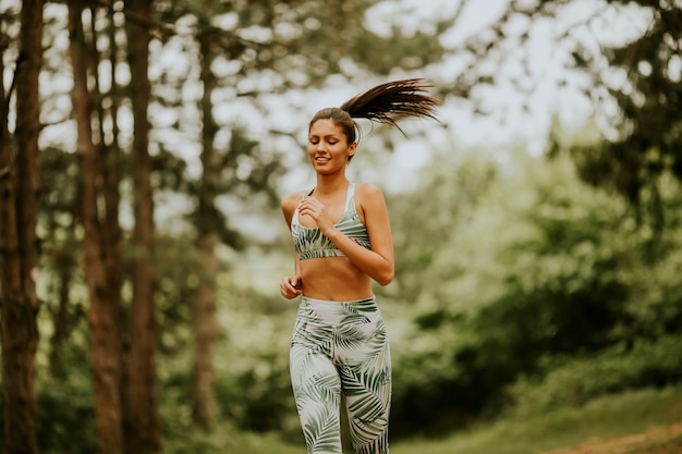 Mulher jovem fitness correndo na trilha da floresta