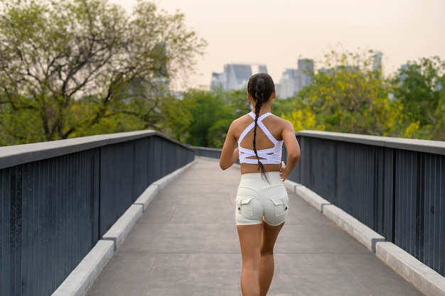 Mulher jovem fitness em roupas esportivas correndo no parque da cidade saudável e estilos de vida
