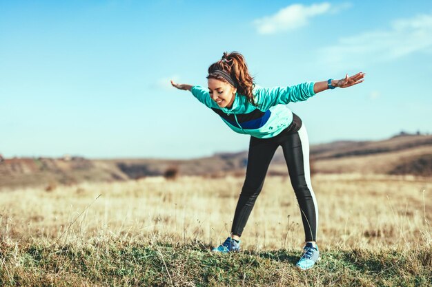 Foto mulher jovem fitness está fazendo exercícios de alongamento depois de correr na liberdade da natureza.