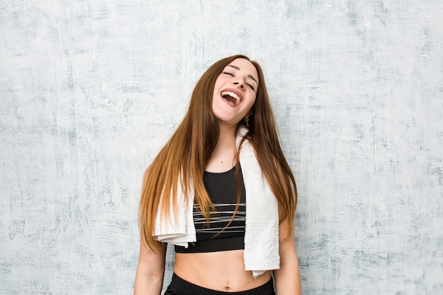 Mulher jovem fitness relaxado e feliz rindo, pescoço esticado, mostrando os dentes.