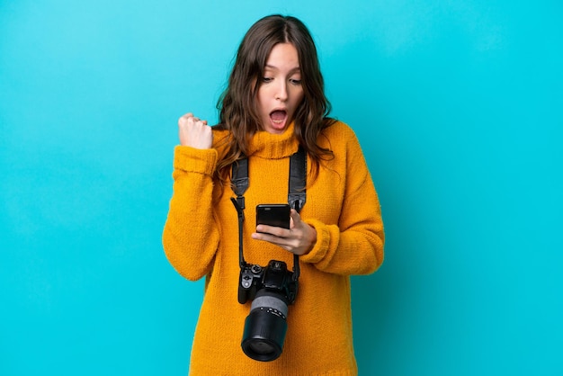 Mulher jovem fotógrafa isolada em fundo azul surpreendeu e enviando uma mensagem