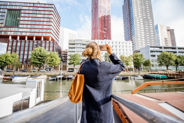 Mulher jovem fotografando arranha-céus modernos no porto da cidade de Rotterdam