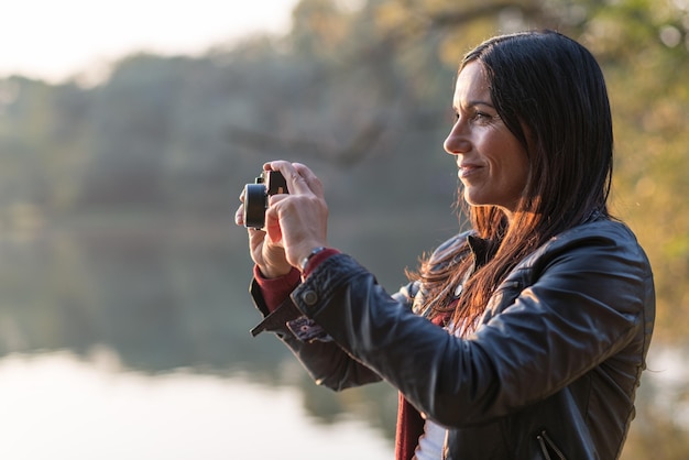 Foto mulher jovem fotografando enquanto está de pé ao ar livre