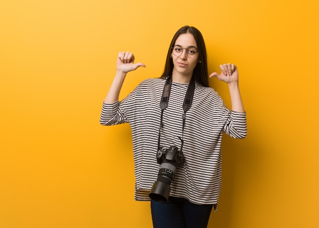 Mulher jovem fotógrafo apontando os dedos, exemplo a seguir