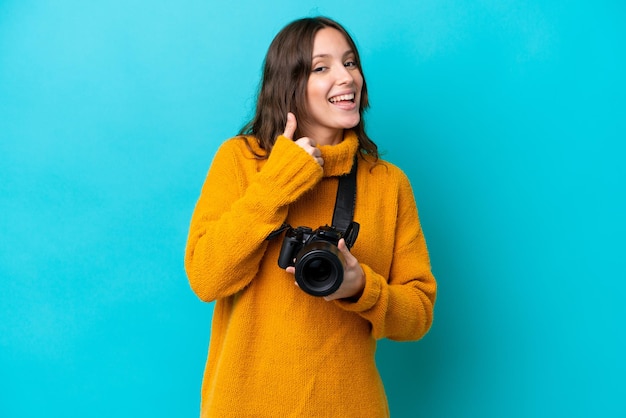 Mulher jovem fotógrafo isolada em fundo azul, dando um polegar para cima gesto