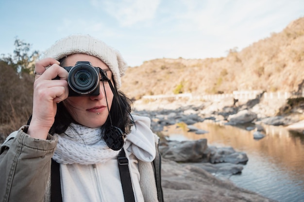 Mulher jovem fotógrafo na montanha olhando pelo visor de sua câmera tirando uma foto