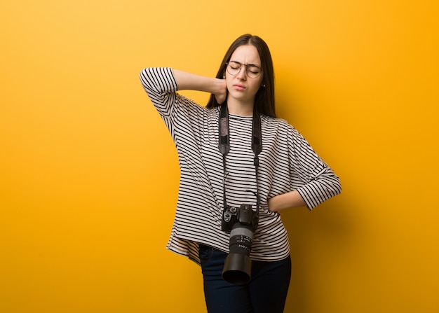 Mulher jovem fotógrafo que sofre de dor no pescoço