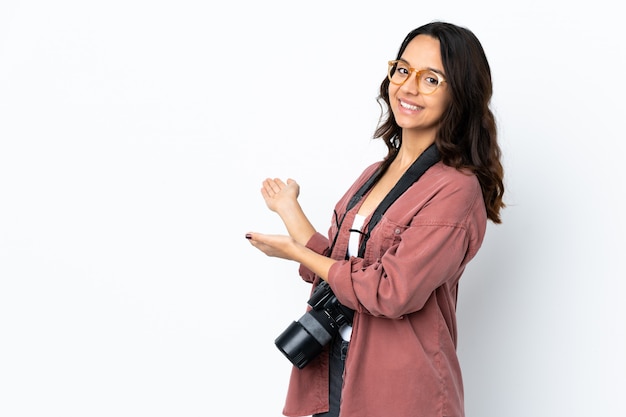 Mulher jovem fotógrafo sobre branco isolado, estendendo as mãos para o lado para convidar para vir