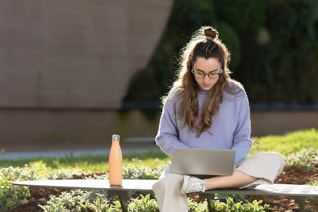 Mulher jovem freelancer trabalhando em seu laptop ao ar livre, sentado em um parque.