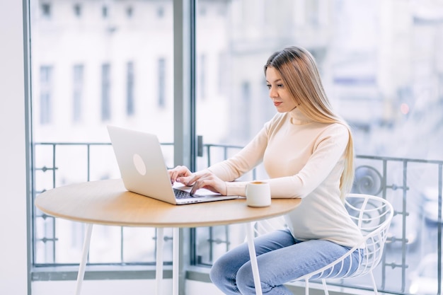 Mulher jovem freelancer usa um laptop em uma mesa de café Sério w