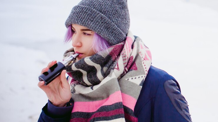 Foto mulher jovem fumando cigarro eletrônico durante o inverno