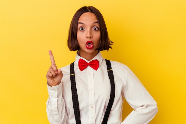 Mulher jovem garçonete de raça mista isolada em fundo amarelo, tendo uma ótima ideia, o conceito de criatividade.