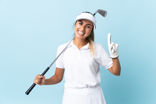 Foto mulher jovem golfista hispânica isolada parede azul mostrando e levantando um dedo em sinal dos melhores