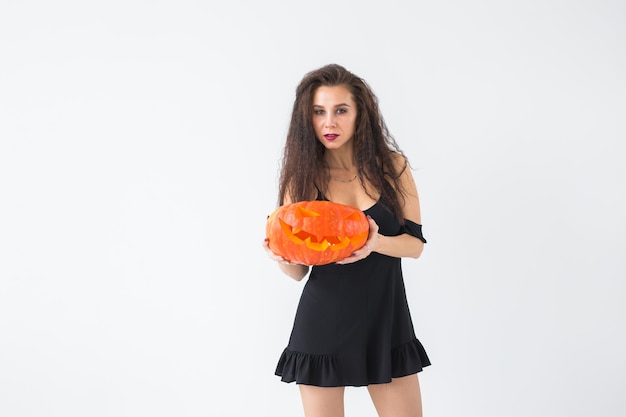 Mulher jovem gótica feliz com fantasia de bruxa de halloween, sorrindo sobre a superfície da sala branca com espaço de cópia