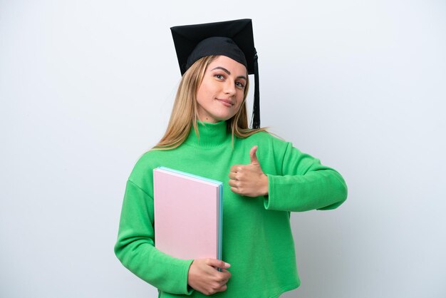 Mulher jovem graduada da universidade isolada no fundo branco dando um polegar para cima gesto
