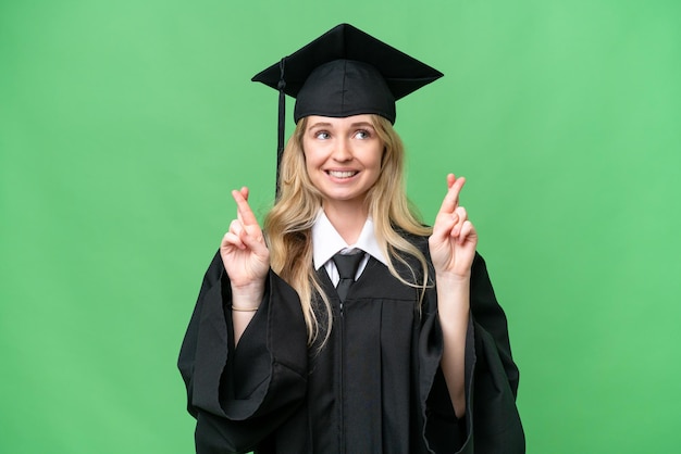 Mulher jovem graduada em inglês da universidade sobre fundo isolado com dedos cruzando