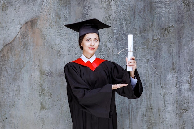 Mulher jovem graduada em vestido segurando o diploma universitário. foto de alta qualidade