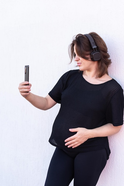 Foto mulher jovem grávida tirando selfie com telefone móvel ou fazendo videoconferência ao ar livre conceito de saúde mental da maternidade e gravidez