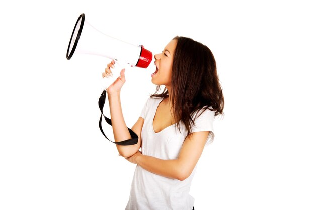 Mulher jovem gritando através de megafone contra fundo branco