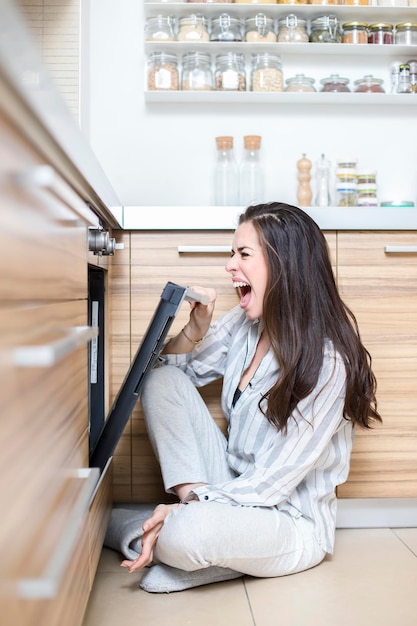 Mulher jovem gritando enquanto estava sentada na cozinha em casa