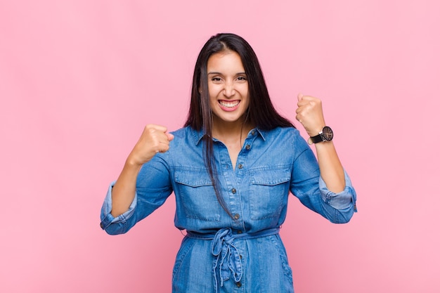 Mulher jovem gritando triunfantemente, rindo e se sentindo feliz e animada enquanto celebra o sucesso