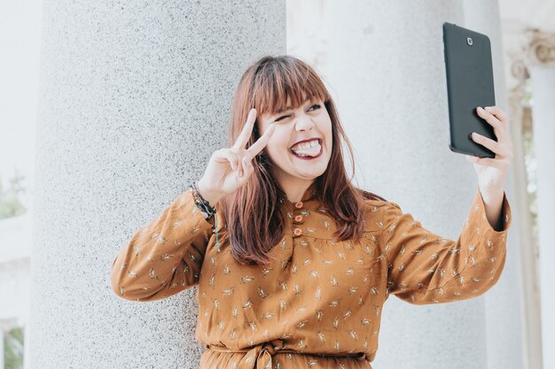 Mulher jovem hippie em um vestido outonal tirando uma selfie enquanto faz uma videochamada, feliz dia moderno, conceitos de liberdade e liberdade, mulher ruiva, estilo de rede social, espaço de cópia