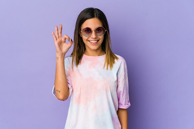 Mulher jovem hippie isolada em roxo alegre e confiante mostrando um gesto de ok.