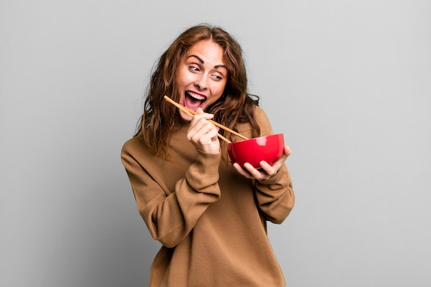 Foto mulher jovem hispânica comendo uma tigela de macarrão japonês