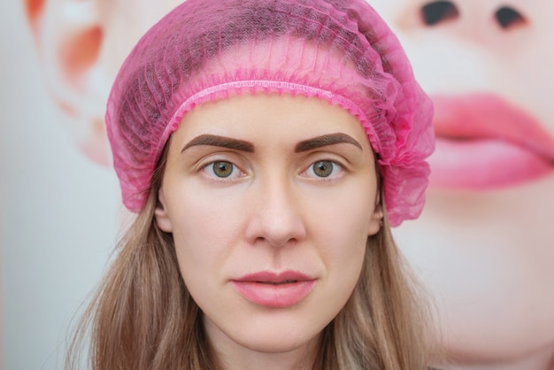 Mulher jovem imediatamente após o procedimento de maquiagem definitiva da sobrancelha