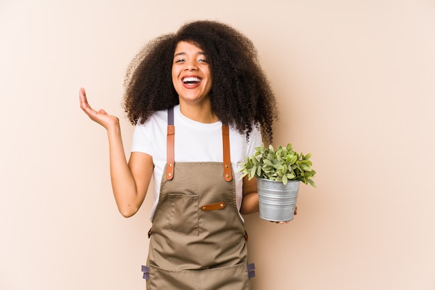 Mulher jovem jardineiro afro segurando uma planta