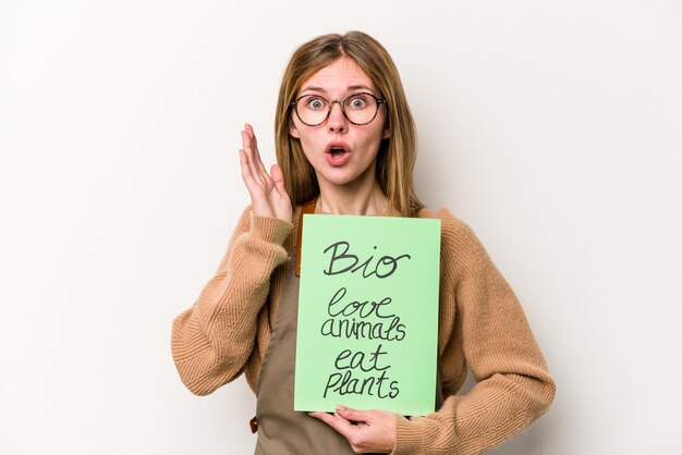 Mulher jovem jardineiro segurando um cartaz bio isolado no fundo branco surpreso e chocado