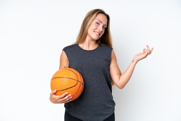 Mulher jovem jogador caucasiano de basquete isolada no fundo branco, estendendo as mãos para o lado para convidar para vir