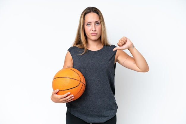 Mulher jovem jogador caucasiano de basquete isolada no fundo branco, mostrando o polegar para baixo com expressão negativa